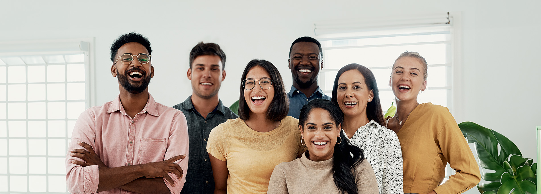 A group of people smiling and posing together with a whiteboard behind them.